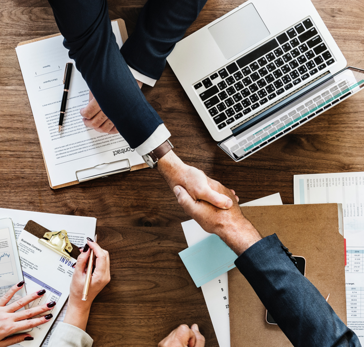 business deal handshake across table